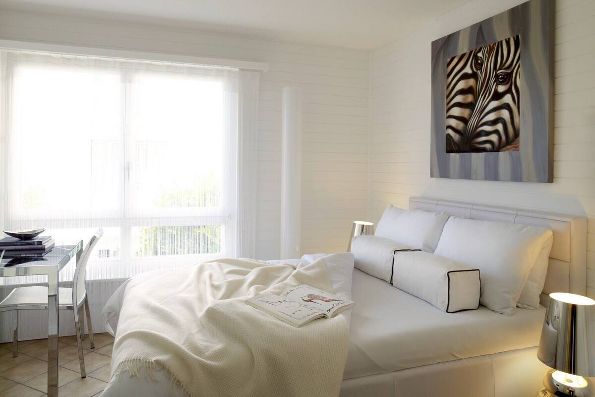 A modern bedroom with a bed, a desk, and a window.
