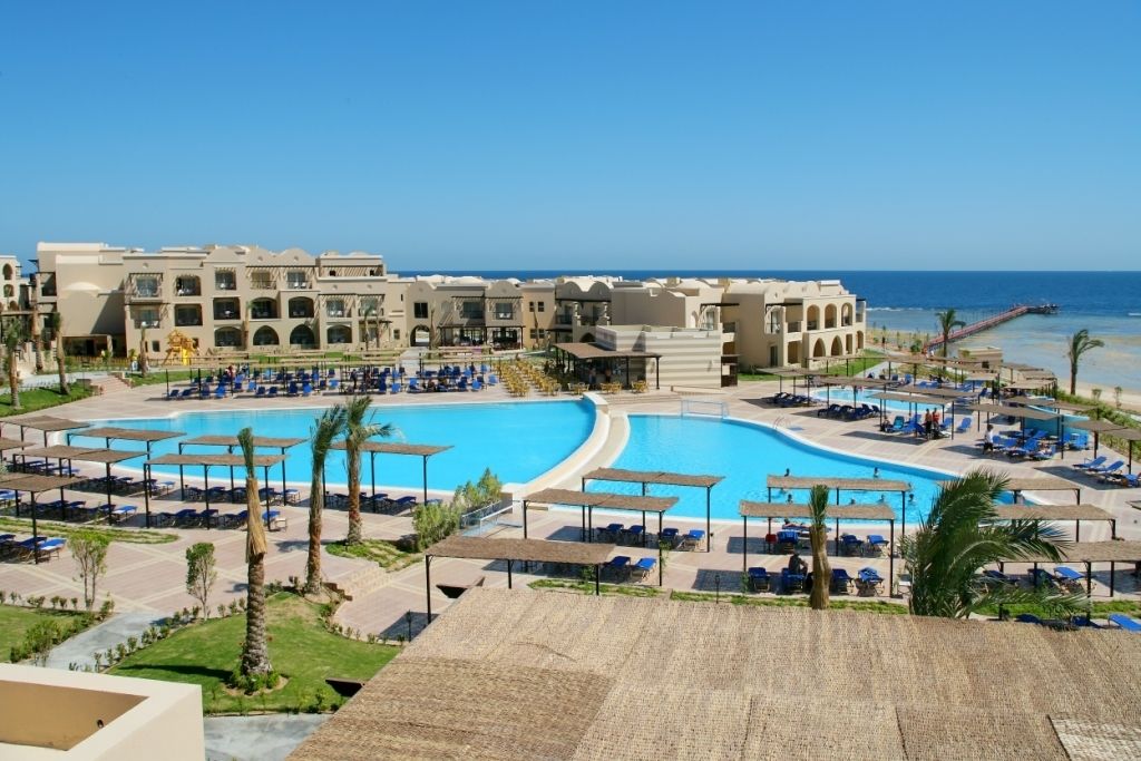 Un resort con una grande piscina centrale, diverse piscine più piccole e una zona spiaggia.