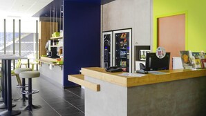 Een receptiebalie met een aanrecht, een telefoon en een computer. Er staan barstoelen bij en een raam met uitzicht.