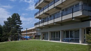 A modern building with multiple balconies, large windows, and a grassy courtyard. - Holiday Hotel Csopak (Csopak)