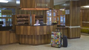 A reception area with a wooden counter, a sign for espresso, and a colorful suitcase. - Holiday Hotel Csopak (Csopak)