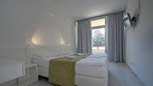 A modern bedroom with a bed, bedside table, and a TV mounted on the wall. - Holiday Hotel Csopak (Csopak)