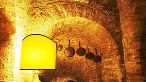 A room with a brick wall, a lamp, and a book on a table. - Hotel La Luma (Montecosaro)