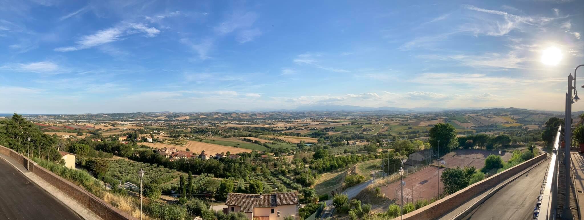 A panoramic view of a rural landscape with fields, houses, and a clear sky.