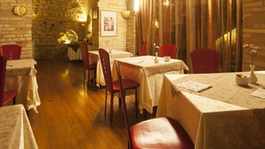 An interior with stone arches, wooden flooring, and tables set for dining. - Hotel La Luma (Montecosaro)