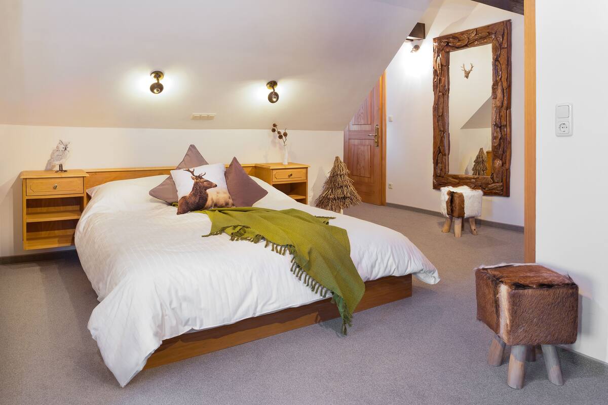 Ein Schlafzimmer mit einem hölzernen Bett, einem Nachttisch, einer Kommode, einem Spiegel und einer kleinen Weihnachtstanne.