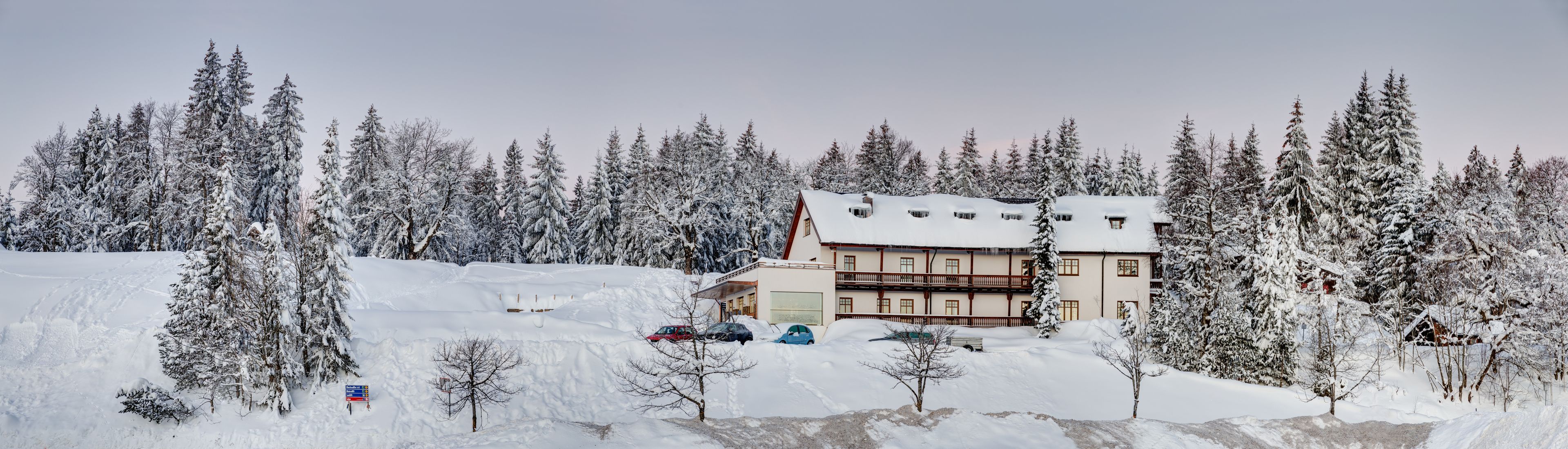 Un hotel con un edificio de varios pisos, rodeado de árboles cubiertos de nieve y un paisaje nevado.