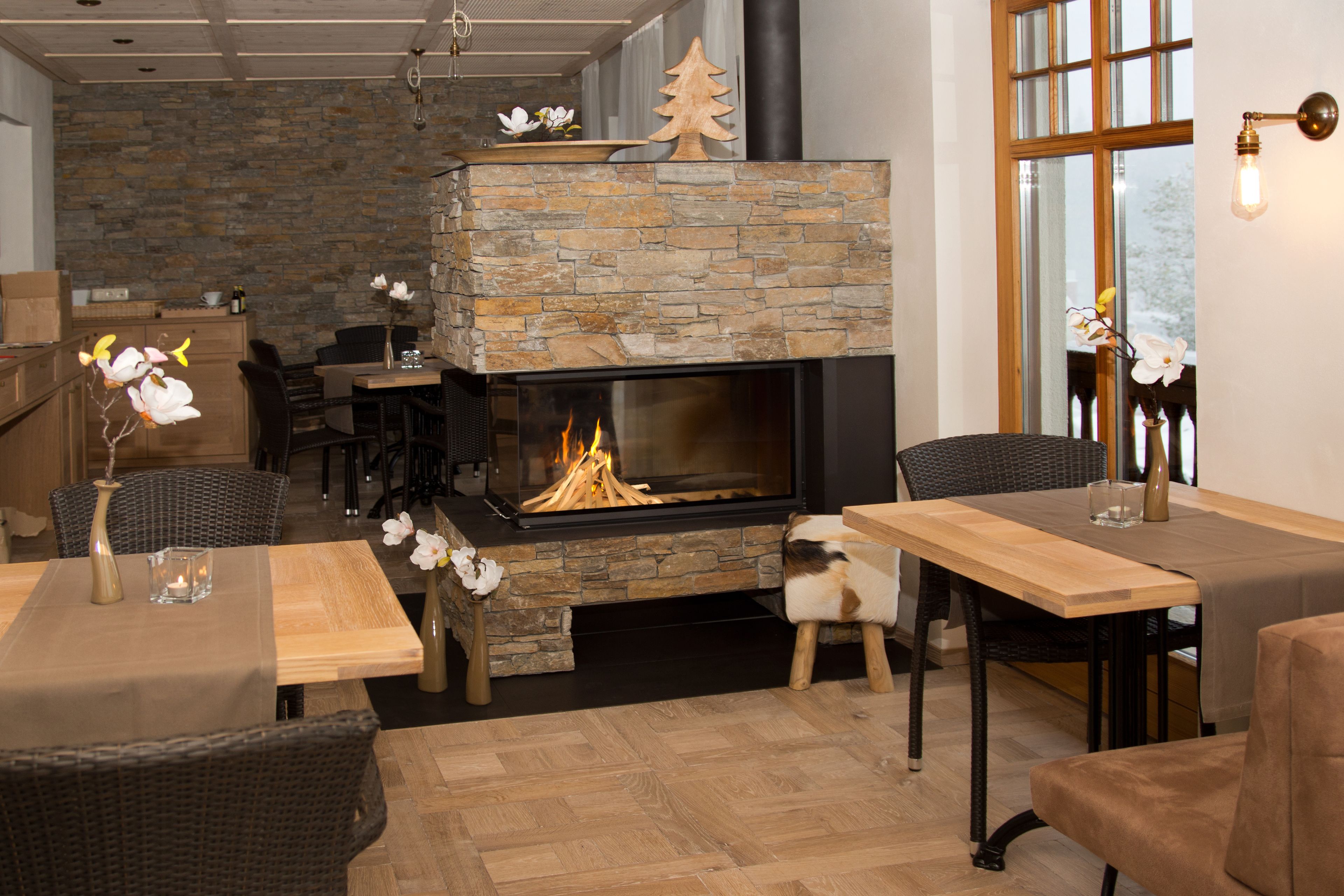 Una sala de estar acogedora con chimenea de piedra, muebles de madera y un ventanal grande.