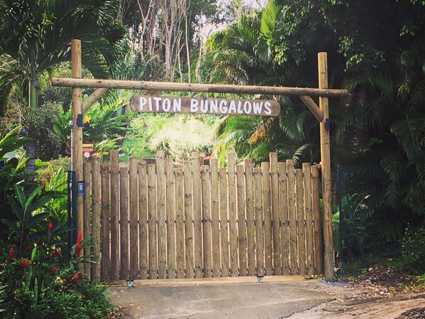A wooden gate with a sign reading "Piton Bungalows" in a lush, green environment. - Piton Bungalows Ecolodges (Deshaies)