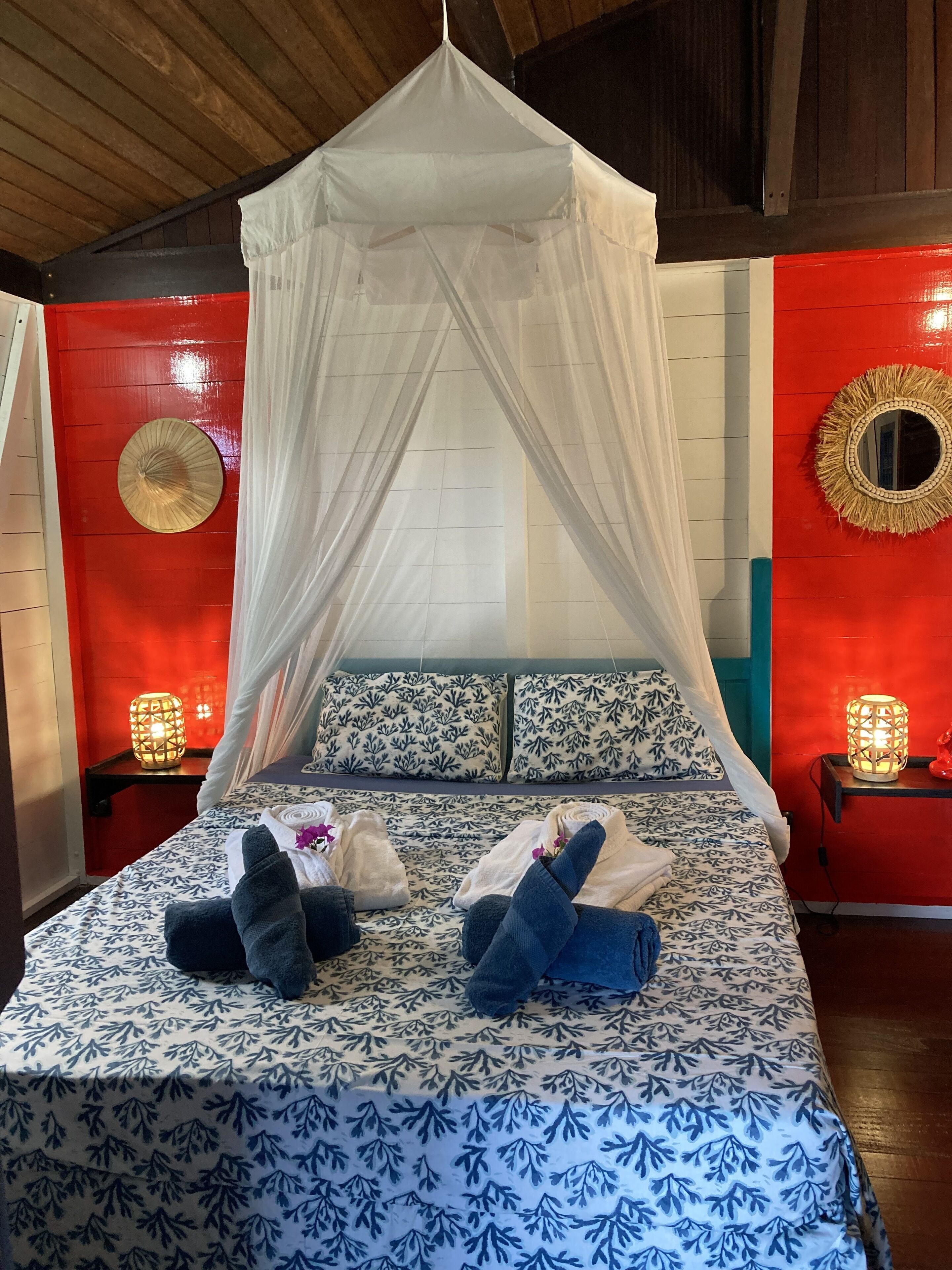 A bed with a canopy, patterned bedding, pillows, and two bedside tables with lamps.