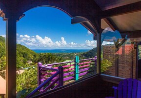 Una habitación con un ventanal grande que ofrece vistas a un paisaje exuberante y al océano.
