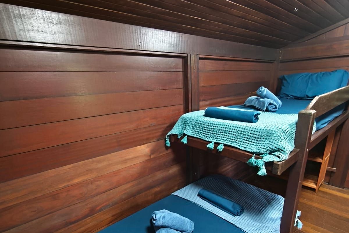 A bunk bed room with wooden walls and a blue mattress.