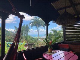 Una habitación con vista al océano, una hamaca, una mesa y sillas.