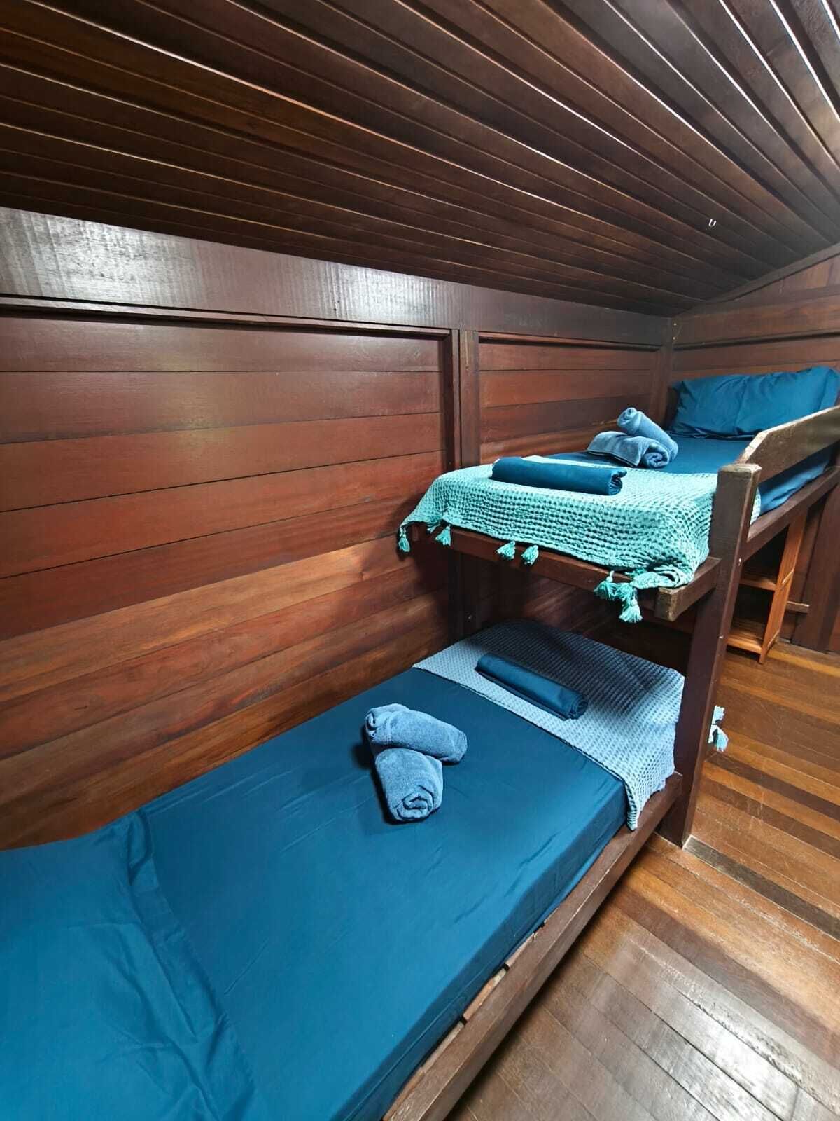 A bunk bed room with wooden walls and a blue mattress.