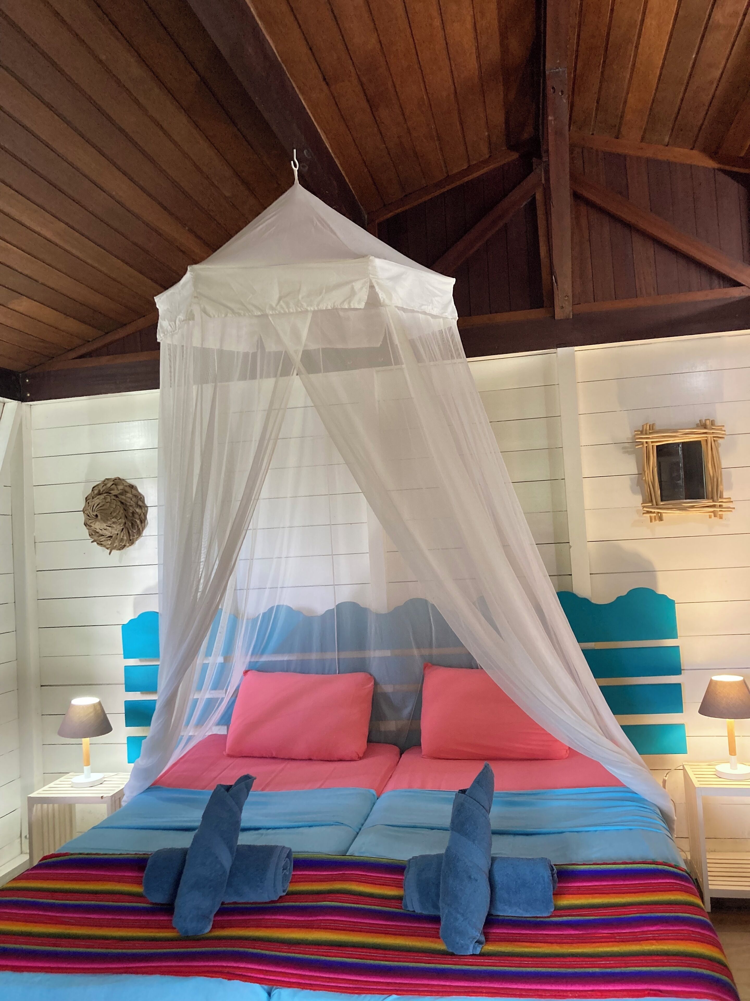 Un lit à baldaquin, avec une literie aux couleurs vives et une couverture à rayures.