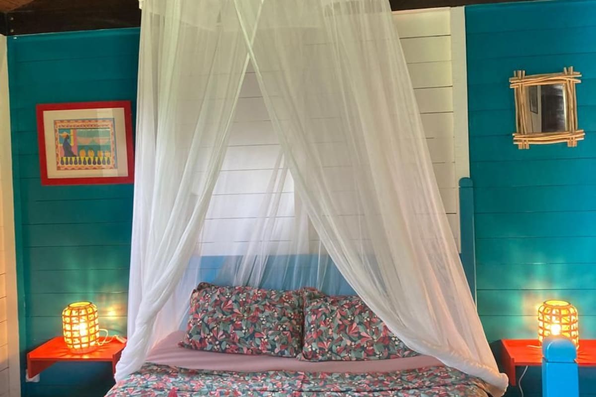 A bed with a canopy, floral bedding, and two bedside lamps.