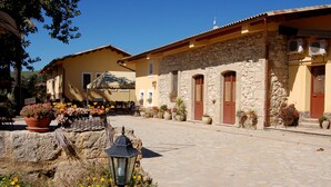 A cobblestone street with a stone building featuring a stone facade and wooden doors. - Il Giardino del sole (Carlentini)