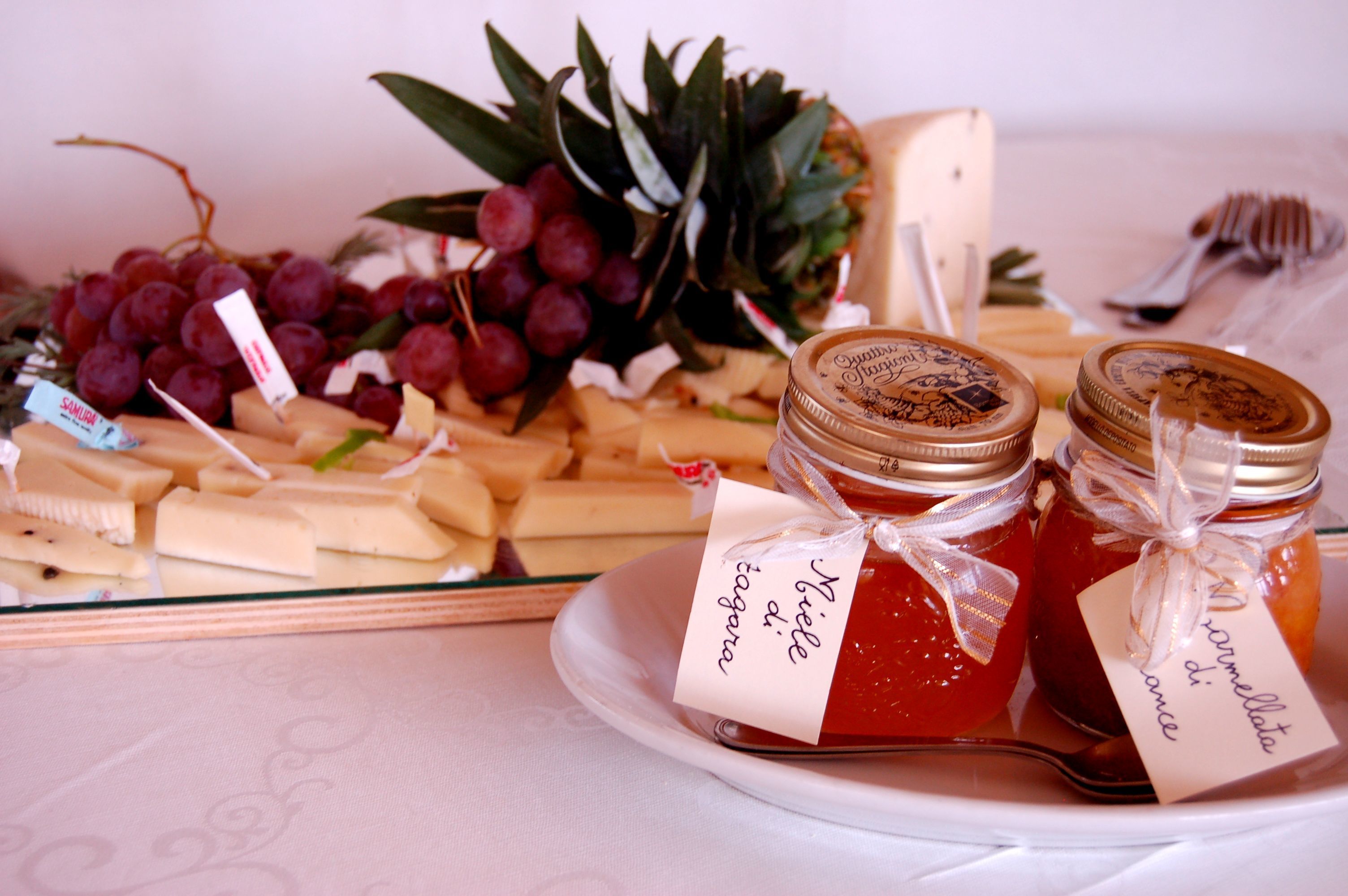 Ein Tisch mit verschiedenen Käsesorten, Trauben und Marmeladengläsern.