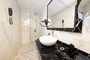A modern bathroom with a marble floor, a white sink, and a black countertop. - Duqqan Deluxe Hotel (Kusadasi)