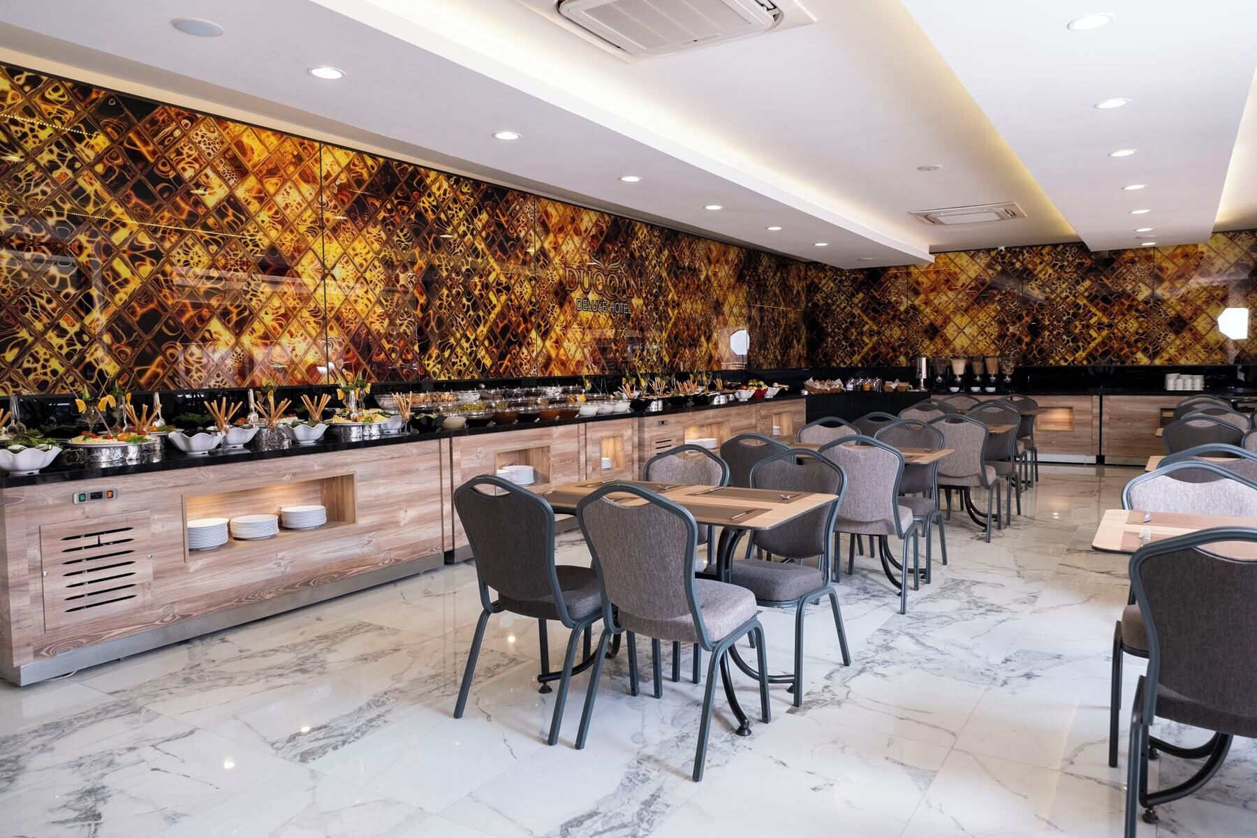 A modern restaurant with a marble floor, a buffet counter with various dishes, and a patterned wall.