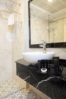 Un baño con lavamanos blanco, encimera de mármol negro y un espejo grande.