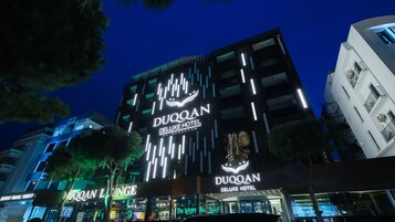 L'esterno dell'Hotel Duoqan Deluxe, con insegne illuminate e un design architettonico moderno.