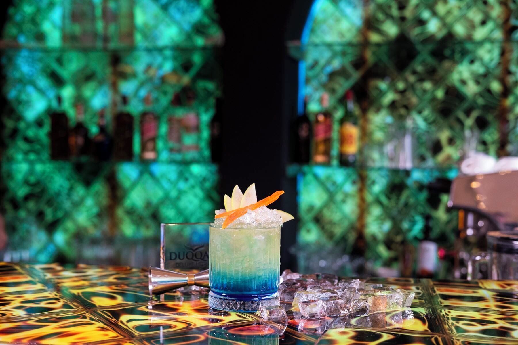 Eine Bar mit Cocktailglas, Eiswürfeln und einer dekorativen Unterlage.