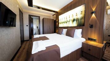 Une chambre d’hôtel moderne avec un grand lit, des panneaux de bois au mur, un téléviseur à écran plat et un tableau.