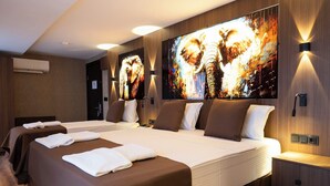 A hotel room with a large bed, two bedside tables, and a wall-mounted TV displaying a dynamic image. - Duqqan Deluxe Hotel (Kusadasi)