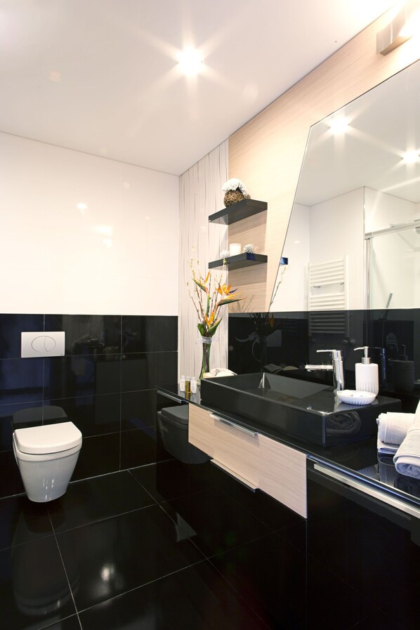 Un baño moderno con inodoro, tocador con espejo y lavamanos.