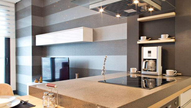A modern kitchen with a central island, built-in appliances, and a dining area with a table set for two. - Platform Merter Suites (Istanbul)