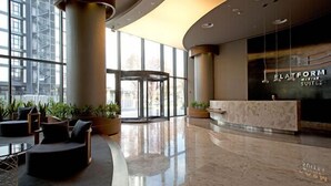 A modern hotel lobby with a reception desk, seating area, and large windows. - Platform Merter Suites (Istanbul)