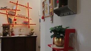 A room with a star decoration, a bulletin board, a shelf with decorative items, a desk with a plant, and a red shelf with a bowl of flowers. - B&B Li Figuli (Lecce)