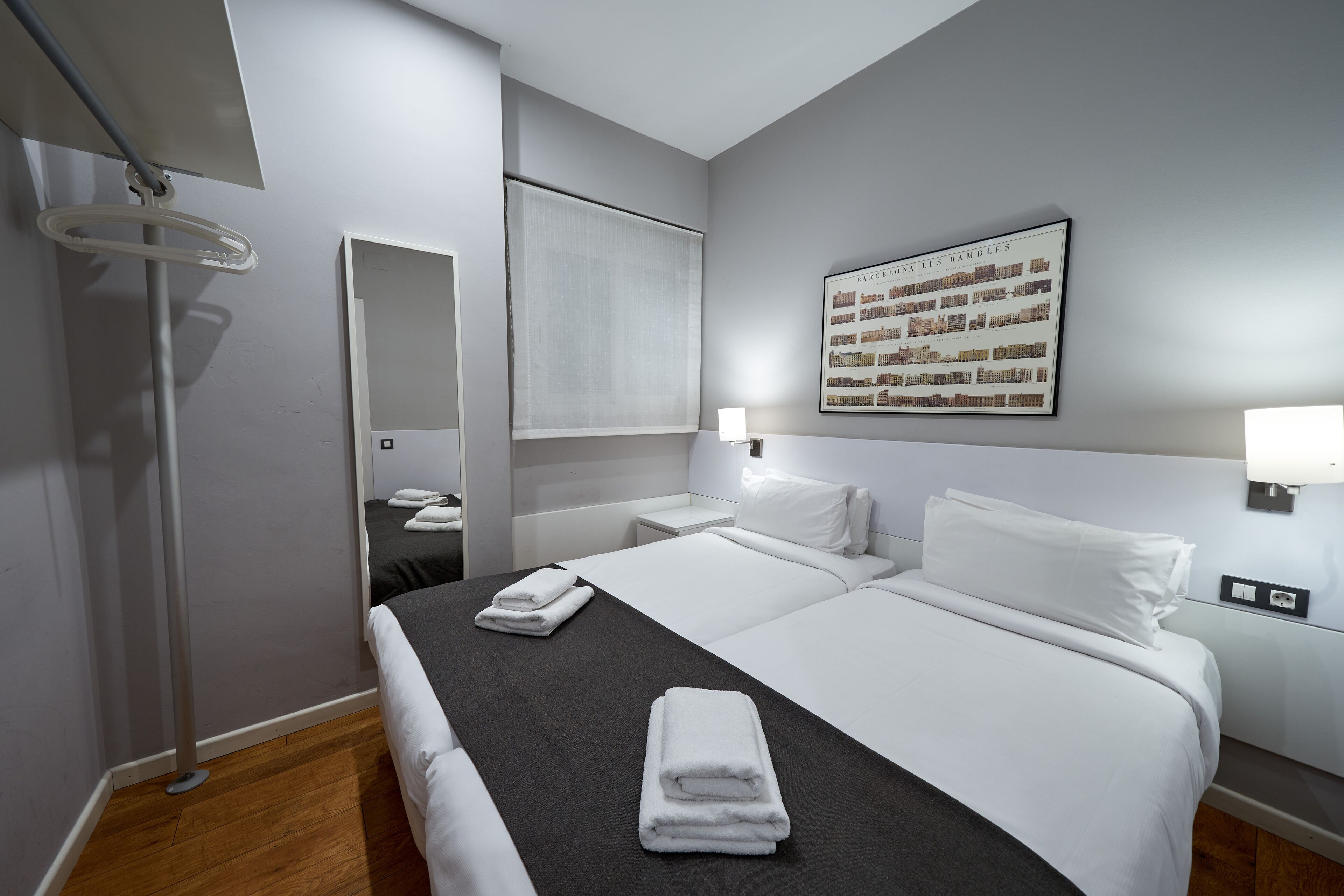 Una habitación de hotel con una cama grande, una lámpara de pie, un espejo y un cuadro en la pared.