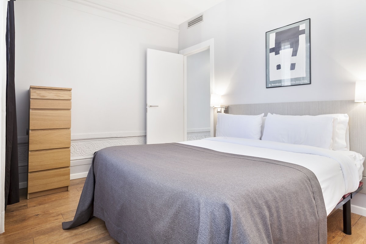 A bedroom with a bed, a wooden dresser, and a door.