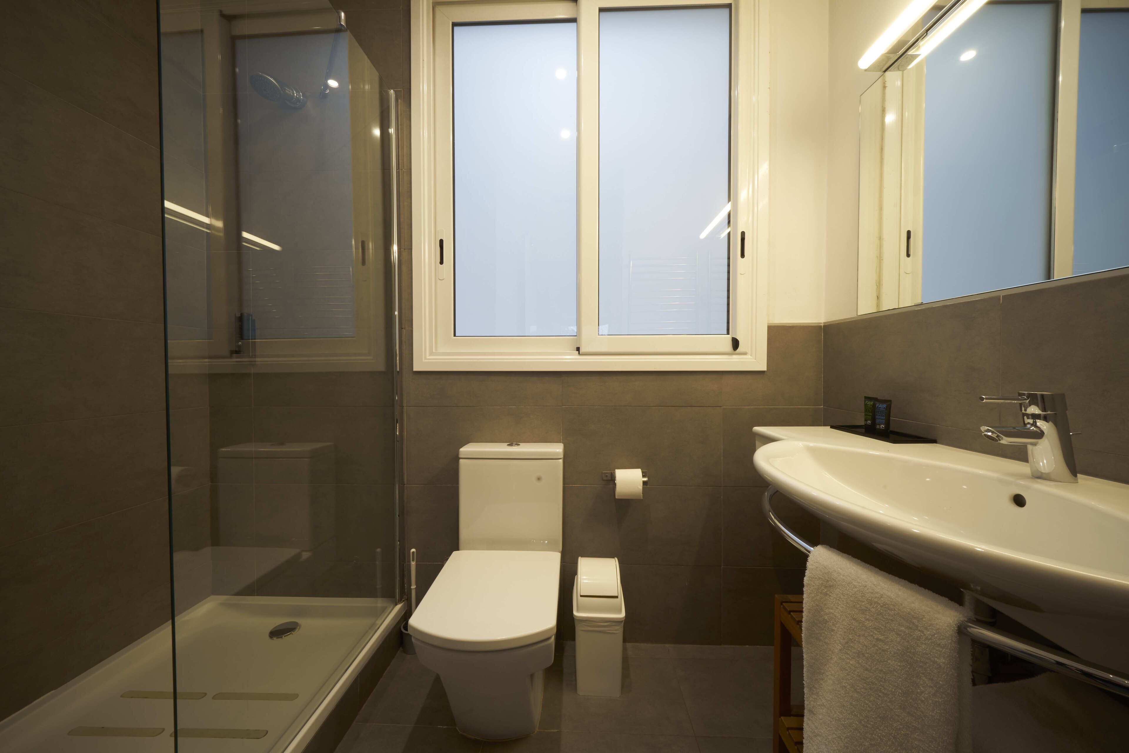 Un baño moderno con cabina de ducha de vidrio, inodoro y lavamanos con toalla.