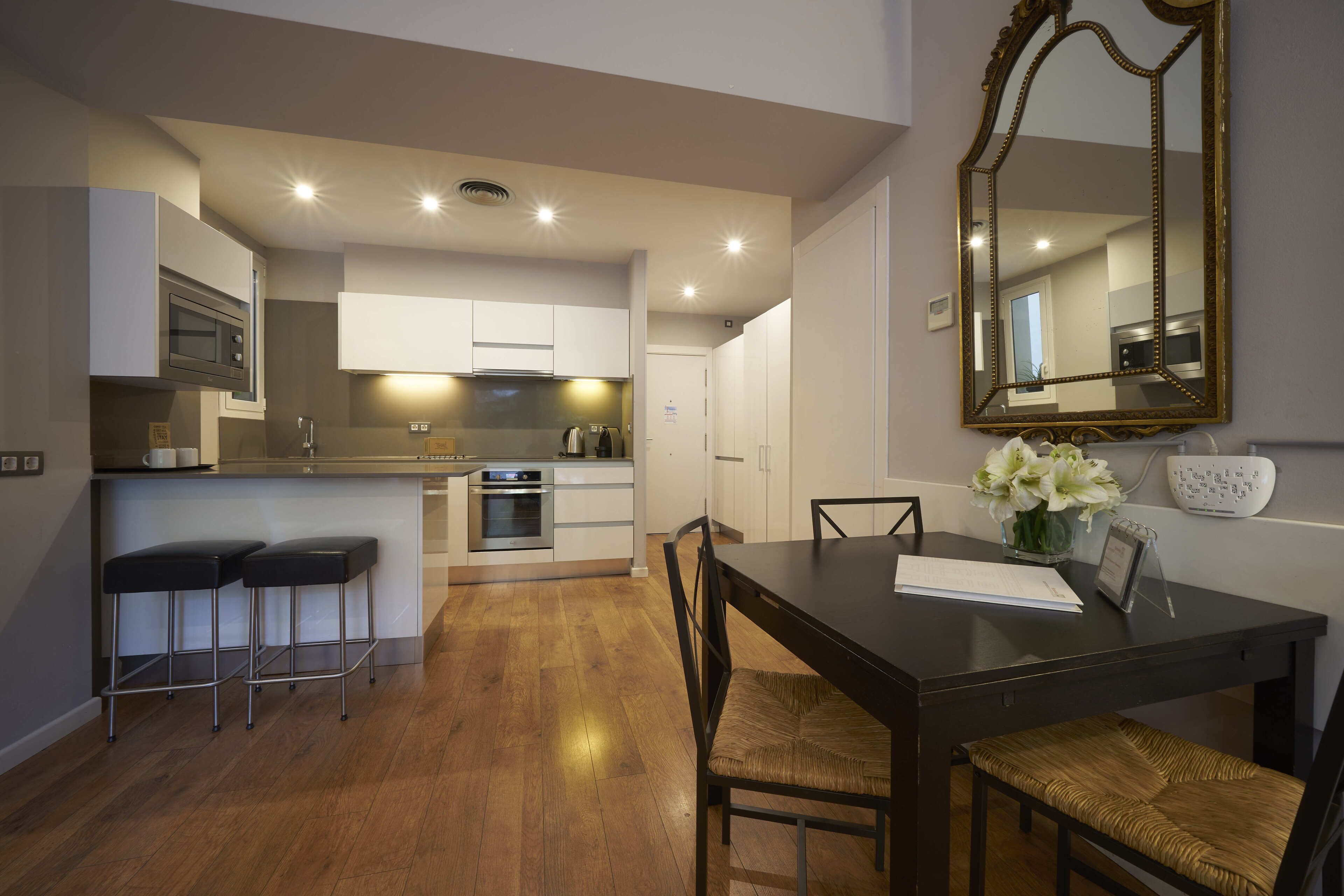 A modern kitchen with white cabinets, a dining table with chairs, and a large mirror on the wall.