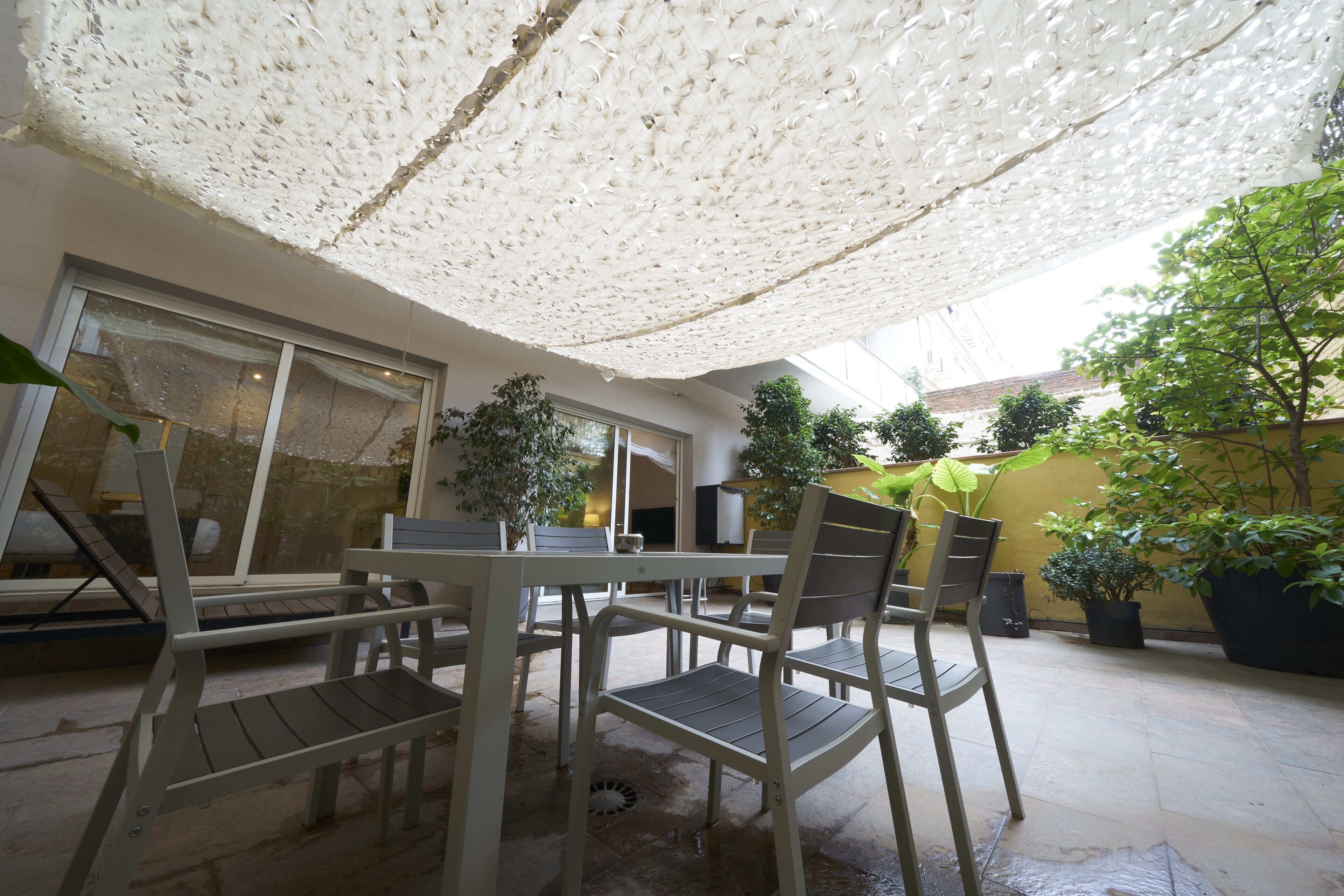 An outdoor patio area with a table and chairs, a covered seating area, and potted plants.