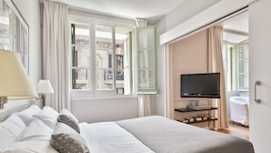 A hotel room with a bed, a television, a window with curtains, and a view of the outside building. - Bonavista Apartments - Passeig de Gracia (Barcelona)