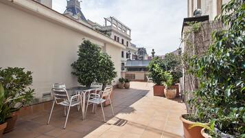 Un cortile con pavimento piastrellato, un tavolo con sedie e piante in vaso.