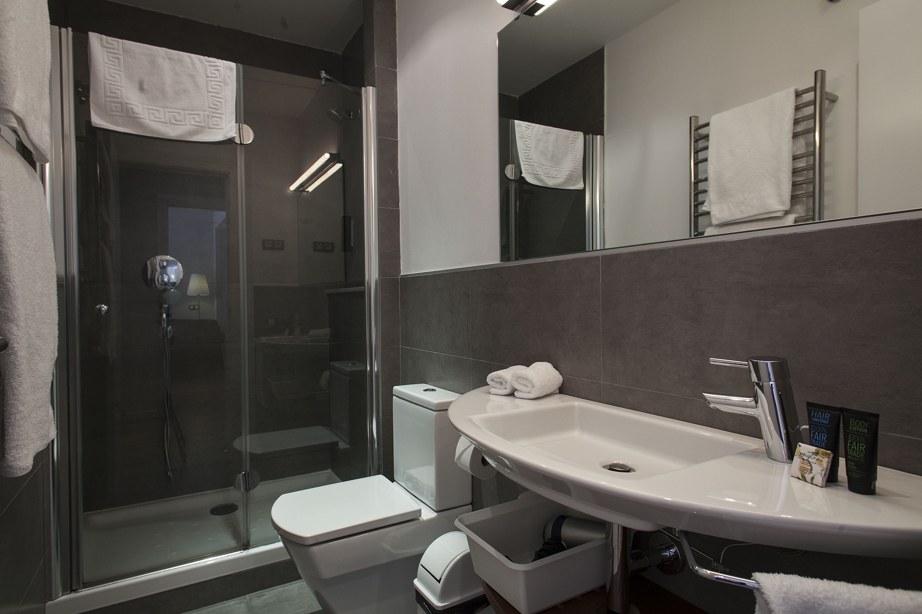 Un baño moderno con cabina de ducha de vidrio, un lavabo blanco y un espejo sobre él.