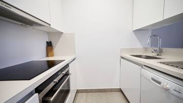 Una cocina compacta con muebles blancos, una campana Bosch, lavavajillas y un lavaplatos.