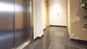 A hallway with a metallic elevator, wooden doors, and a tiled floor. - Bonavista Apartments - Virreina (Barcelona)