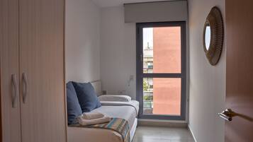 Een slaapkamer met een bed, een kledingkast, een raam en een spiegel aan de muur.