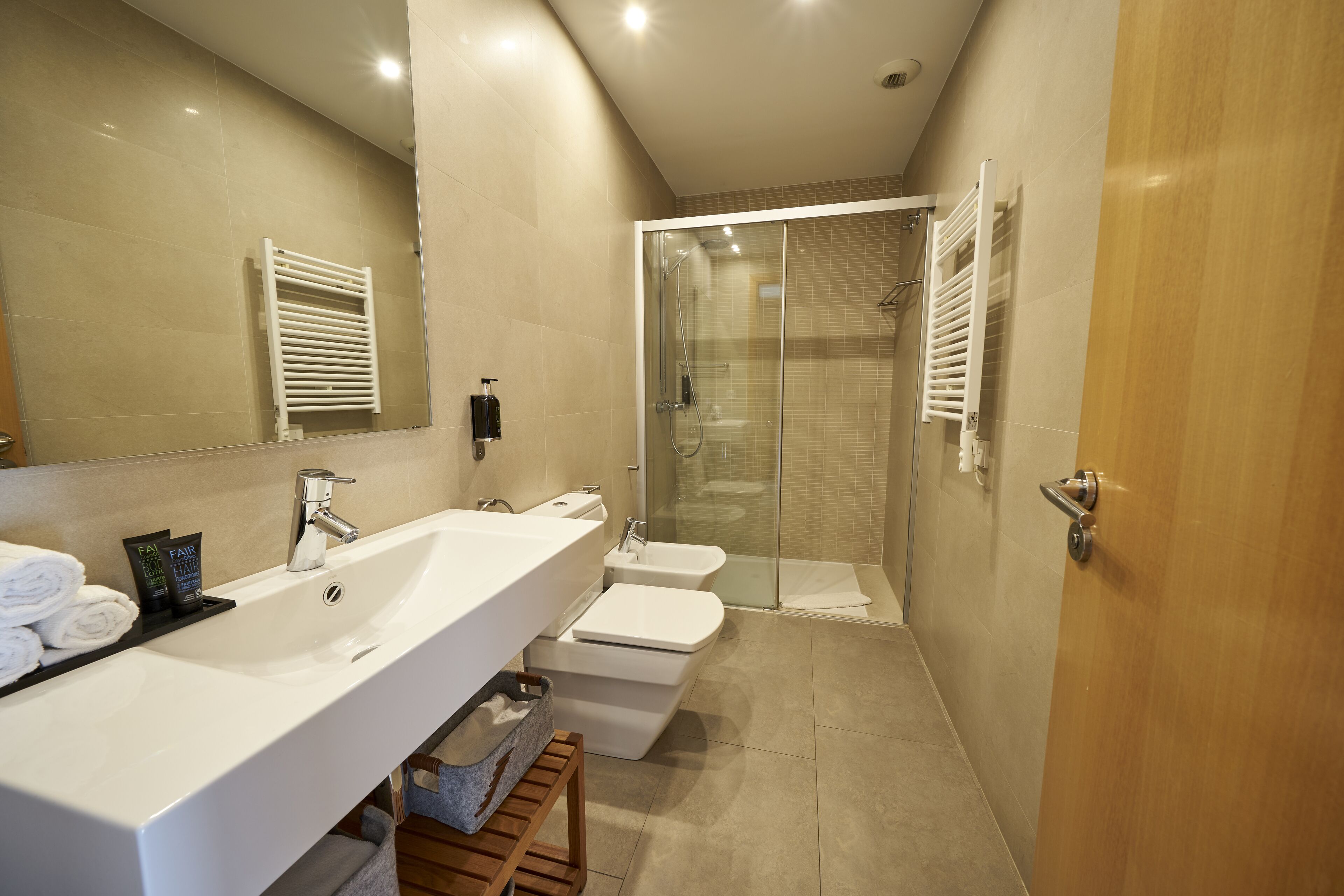 Un baño moderno con un lavamanos grande, inodoro y ducha con mampara de vidrio.
