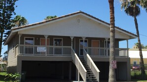 Ein zweistöckiges Gebäude mit Balkon, Treppe und Garage.