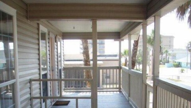 Eine überdachte Veranda mit Holzboden und weißen Geländern.
