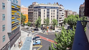 Una calle urbana moderna con edificios de varios pisos, un paso de peatones y un coche azul.
