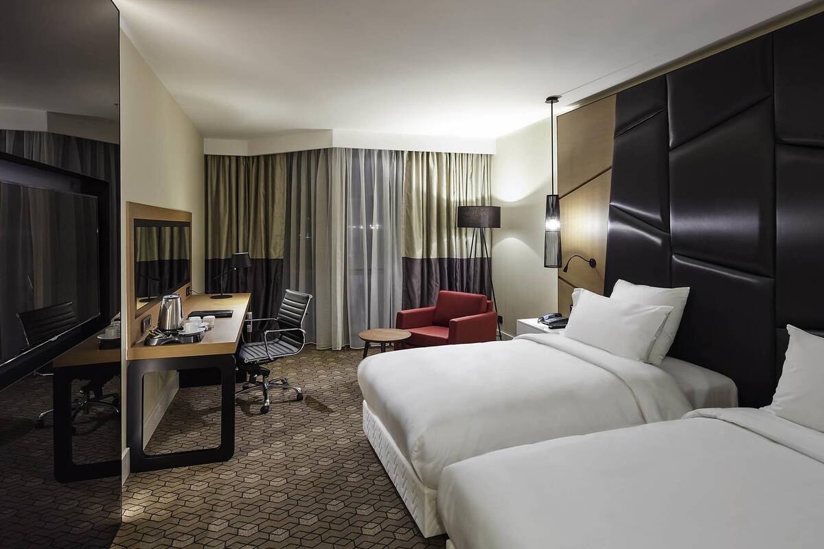 Een hotelkamer met een bed, een bureau met stoel, een televisie en een lamp.