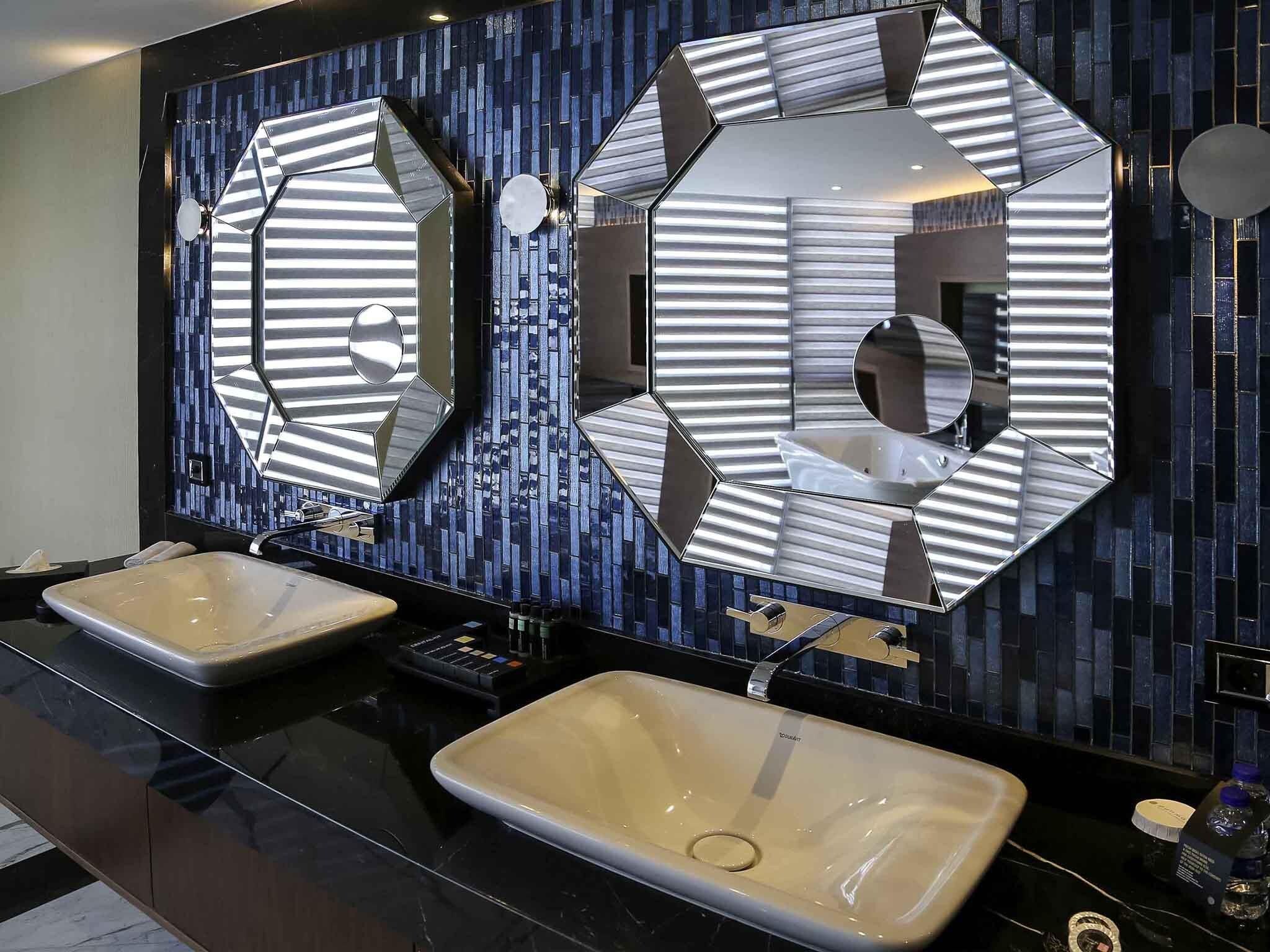 Un baño moderno con dos lavamanos, un espejo grande y encimera negra.